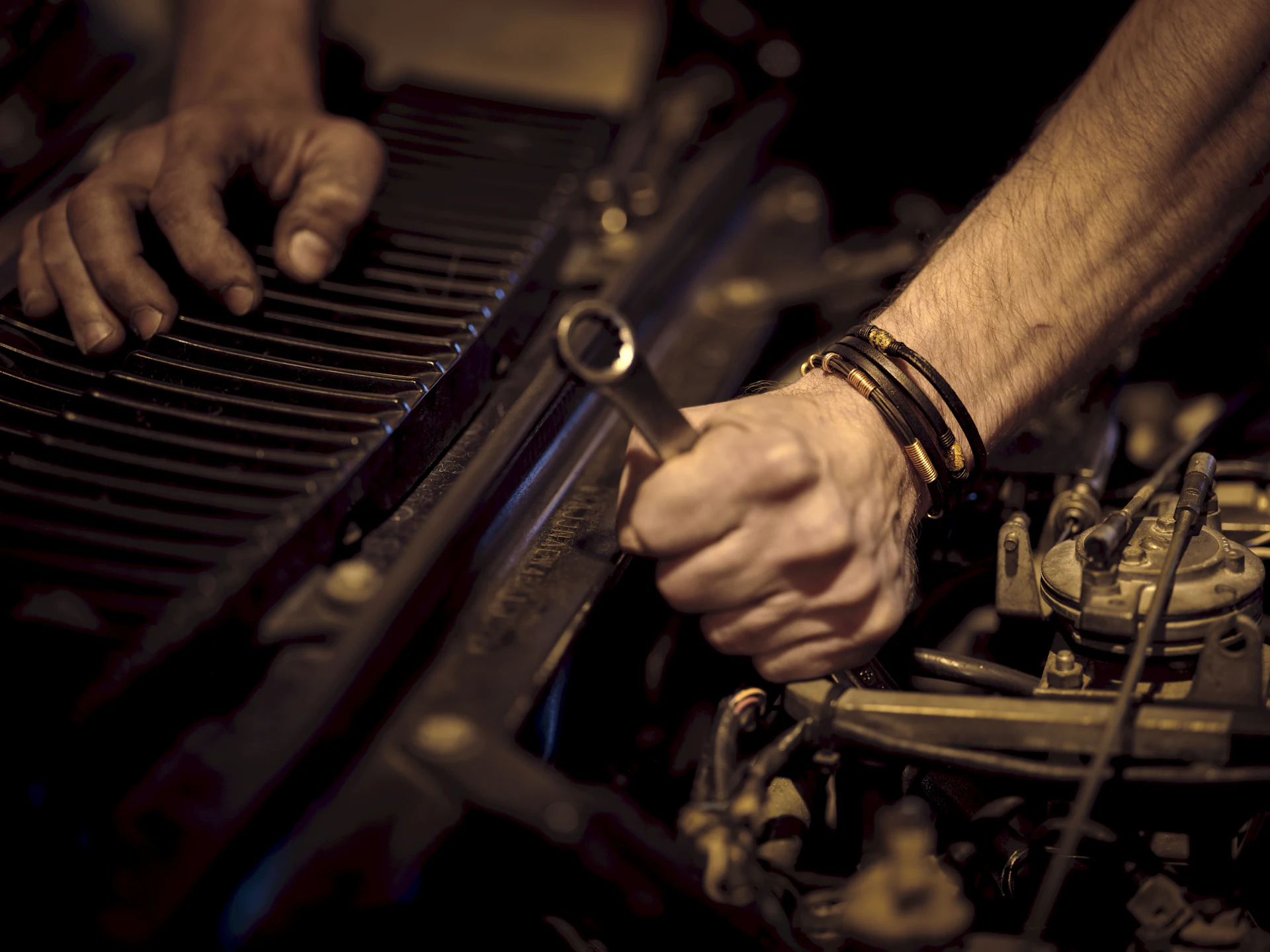 Hands using a wrench in an engine bay